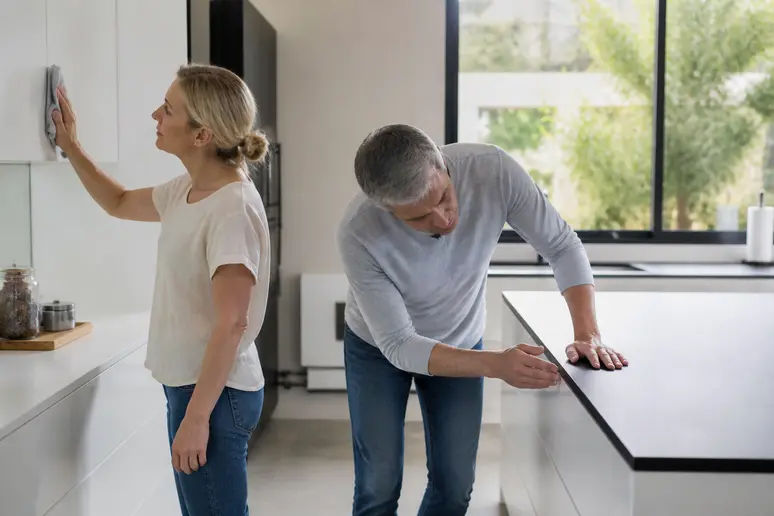 Un couple français examine attentivement la qualité des finitions d'une cuisine moderne et bien éclairée.