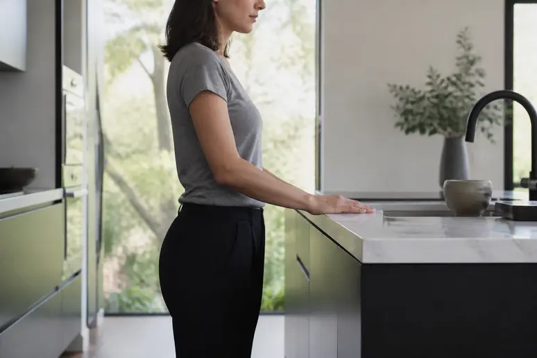 Personne testant la hauteur ergonomique du plan de travail cuisine avec les bras fléchis à angle droit