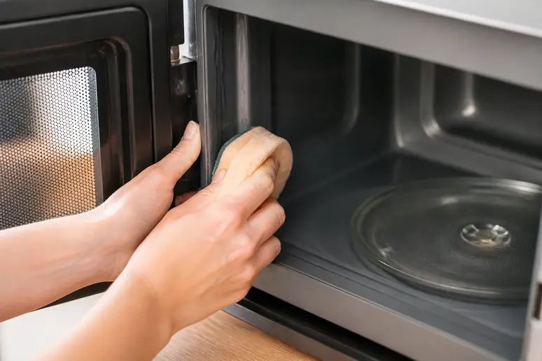 Nettoyage minutieux du joint d'étanchéité d'un four à micro-ondes avec une éponge