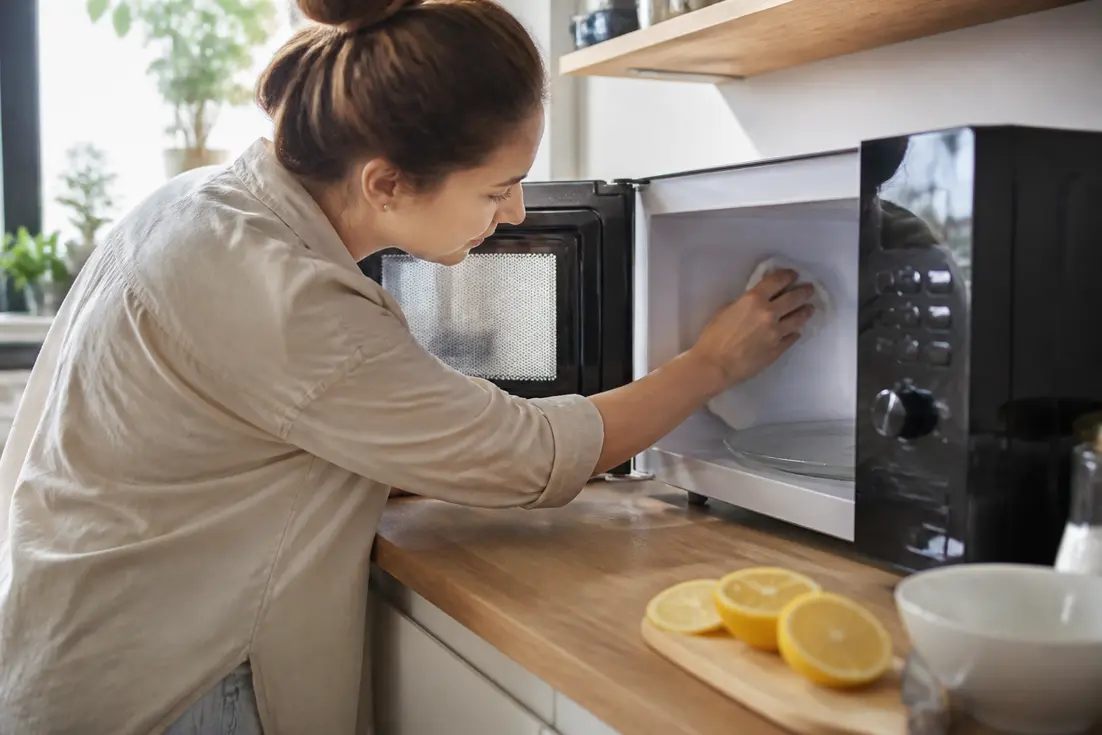 Une personne nettoie l'intérieur de son appareil après avoir fait chauffer un bol pour nettoyer micro-ondes citron.