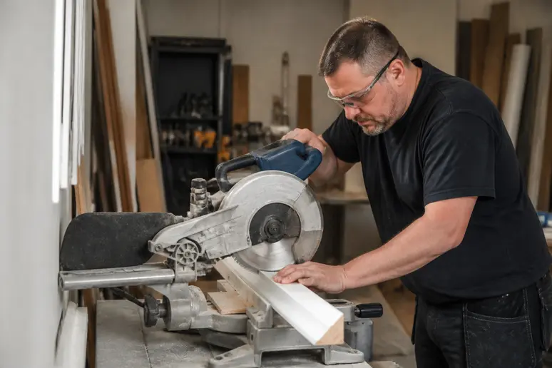 Artisan réalisant une coupe d'onglet sur une plinthe pour un angle de mur complexe