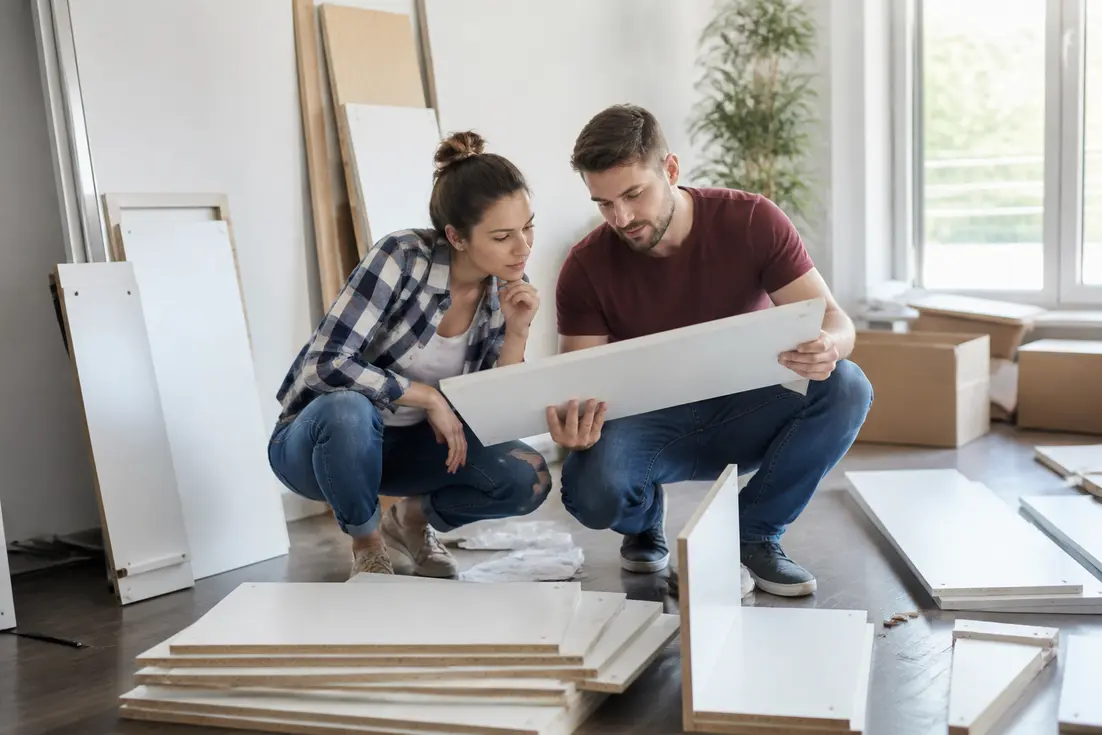 Un couple assemble des éléments de mobilier lors d'un achat cuisine direct usine pour leur rénovation.