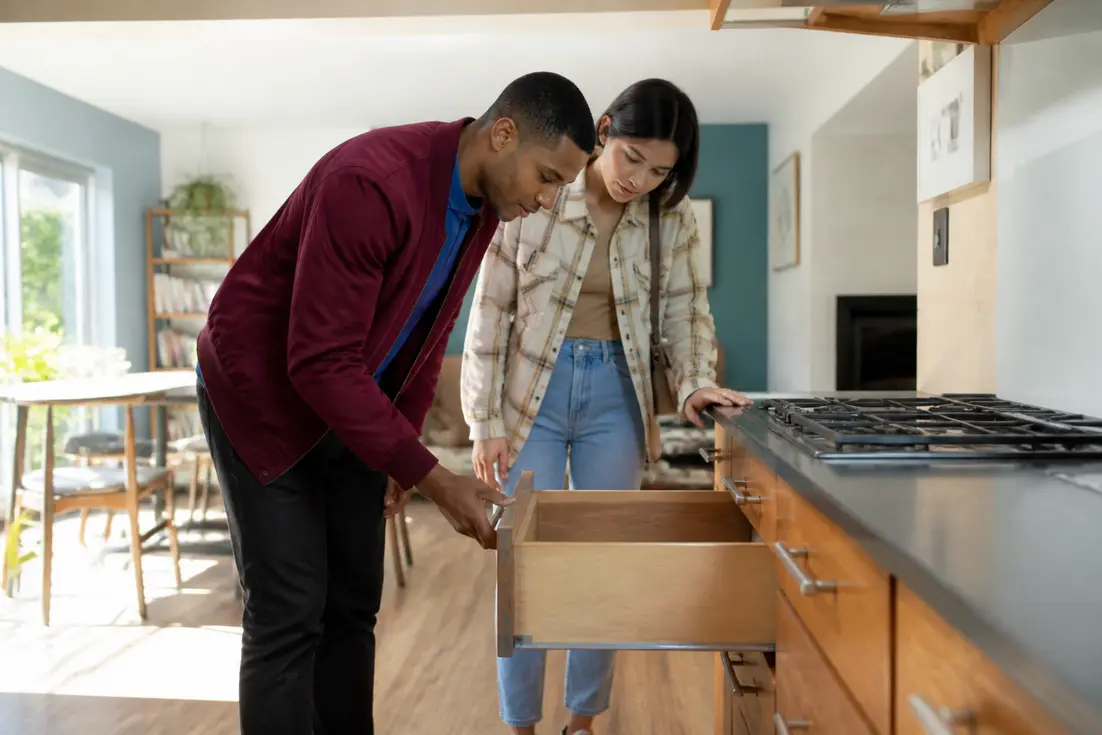 Un couple examine les meubles d'une cuisine aménagée d'occasion pour se faire un avis cuisine alno.