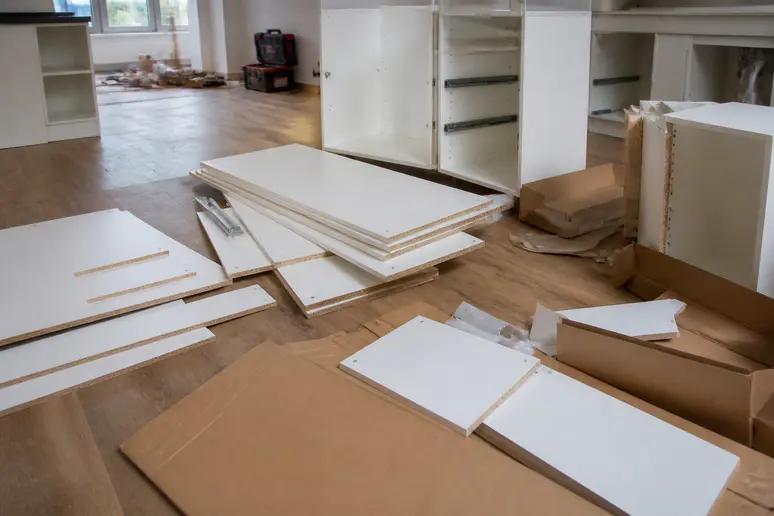 Cartons de meubles de cuisine ouverts révélant des éléments à assembler lors d'une livraison