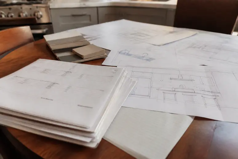 Dossier de commande de cuisine et plans d'aménagement étalés sur une table en bois