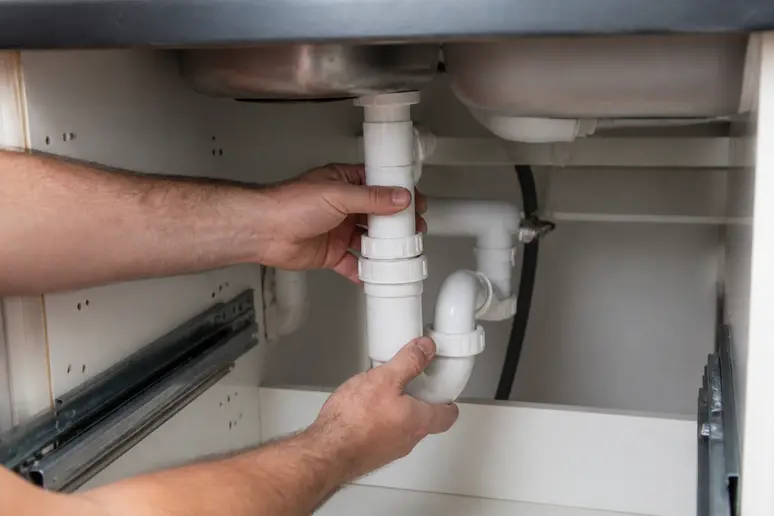 Ajustement d'un siphon en PVC dans un meuble sous évier aux dimensions restreintes